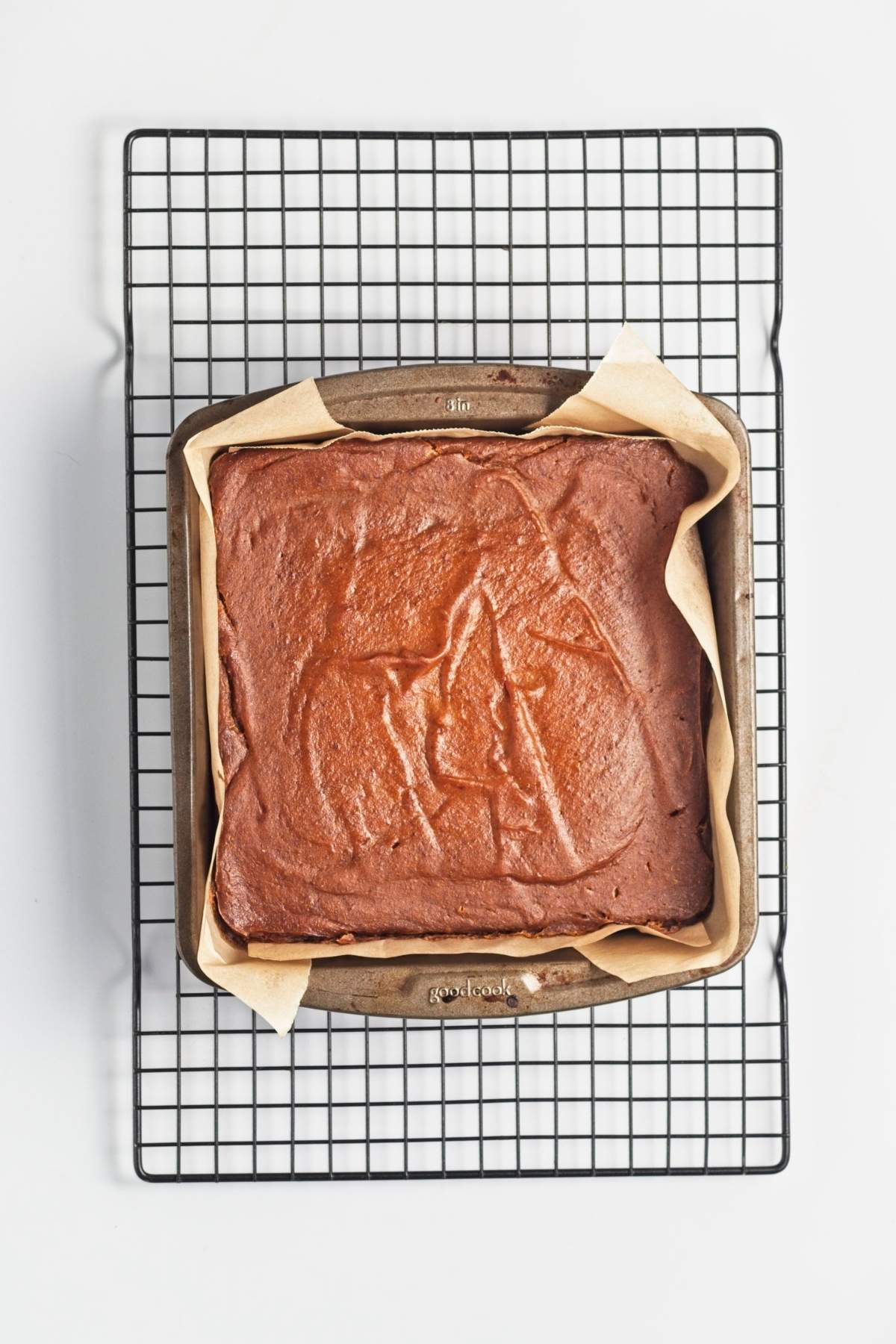 Baked pumpkin filling in a parchment-lined square pan on a cooling rack.