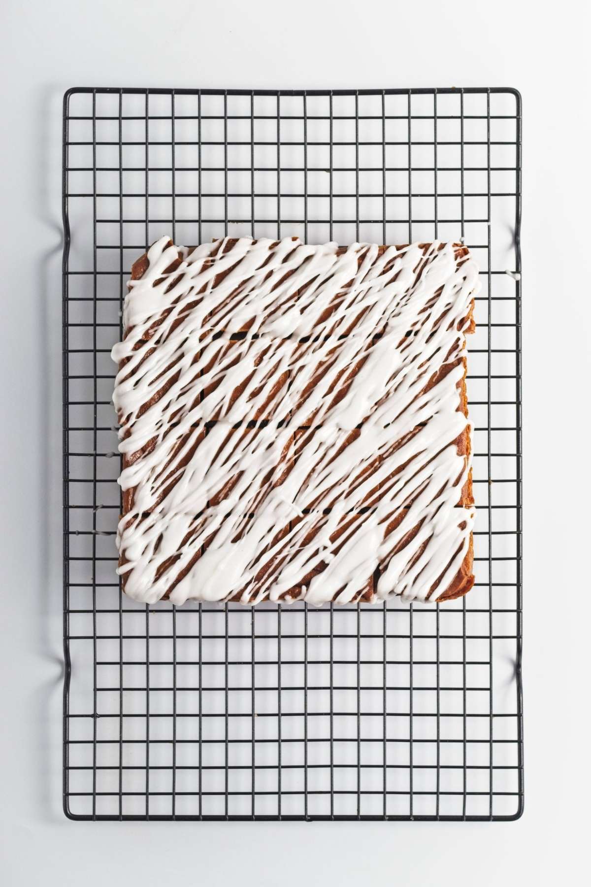 Pumpkin slab topped with white glaze on a cooling rack.