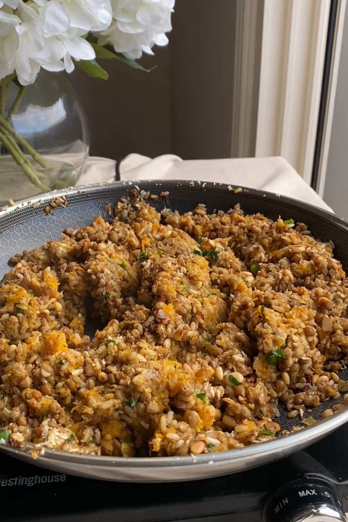 Rice and lentil filling mixed with toasted pine nuts and chopped parsley in a skillet.