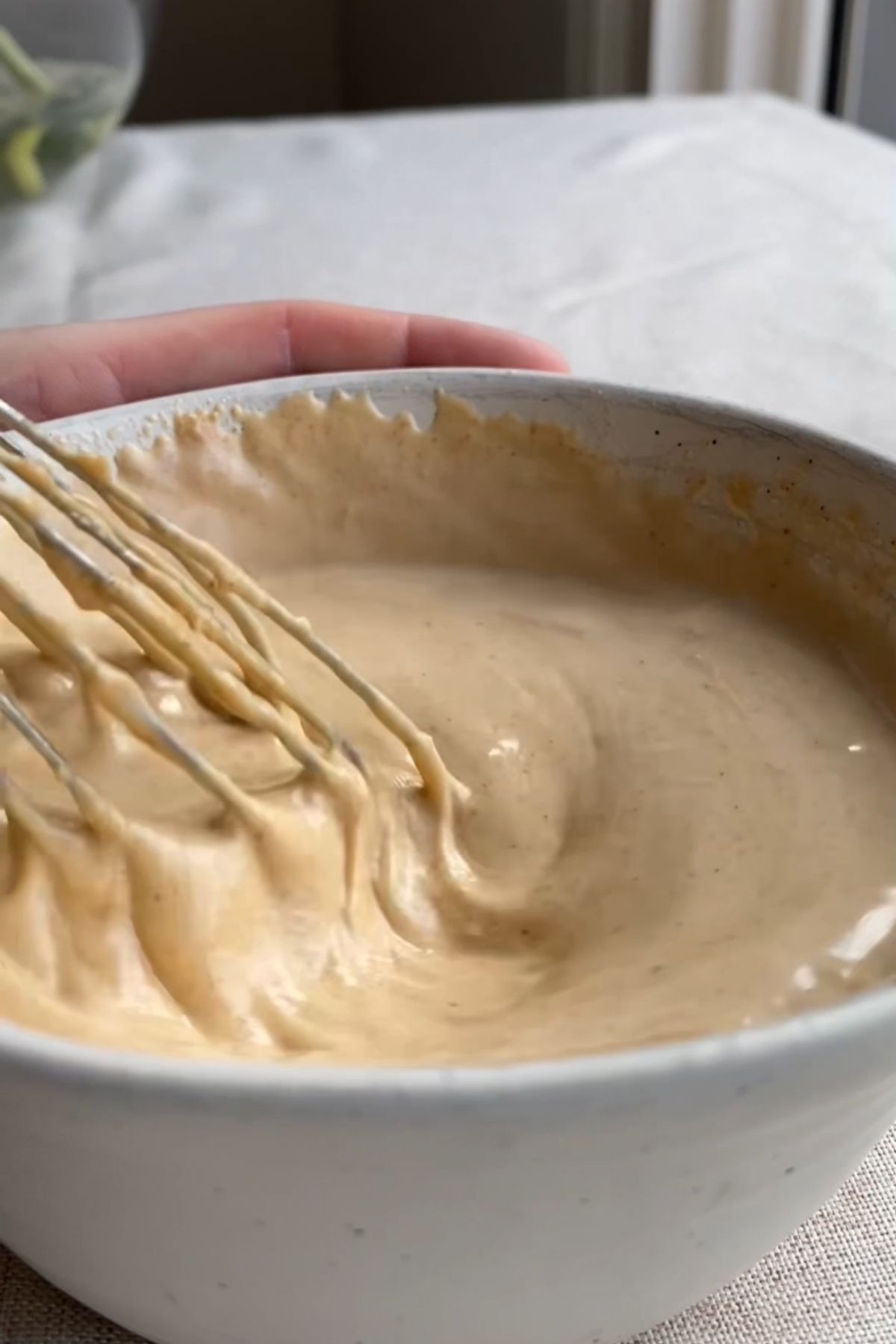 Creamy tahini sauce being whisked until smooth.