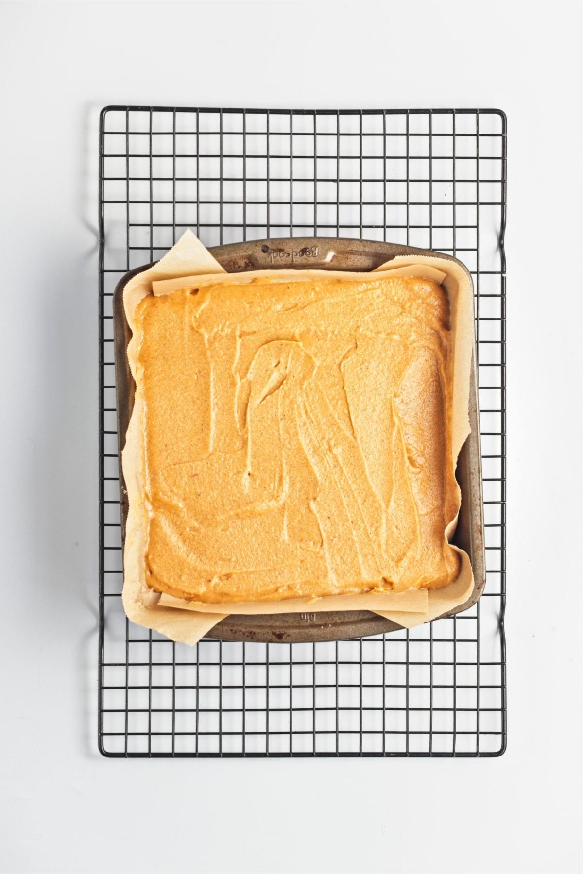Sweet potato filling spread evenly over a baked crust in a square pan.