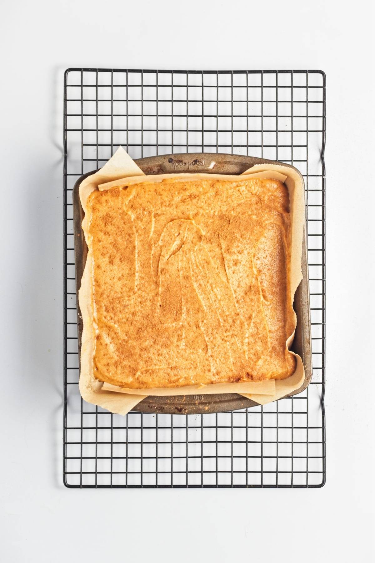 Sweet potato filling dusted with cinnamon in a parchment-lined baking pan.