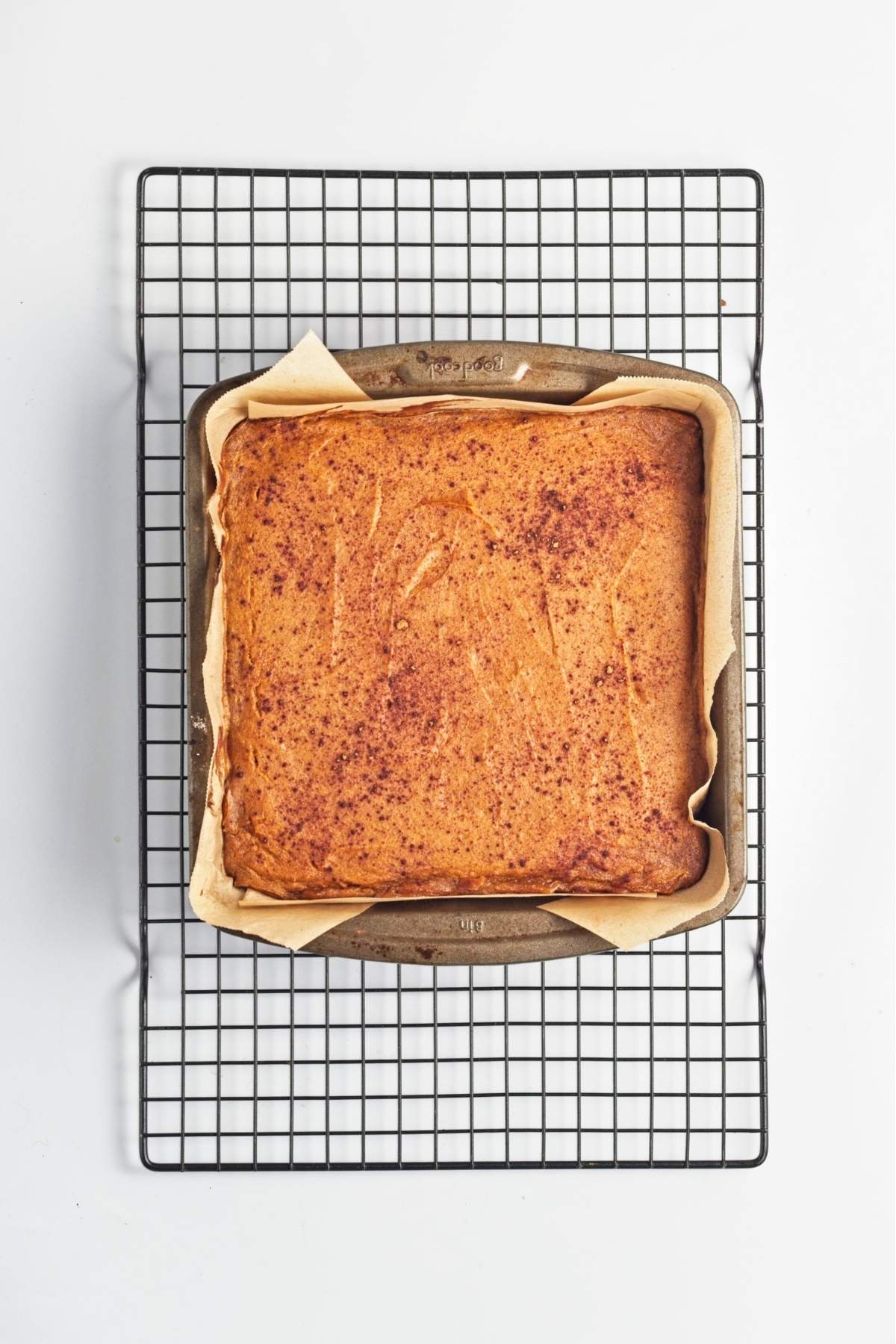 Baked sweet potato bars cooling in a parchment-lined square pan.