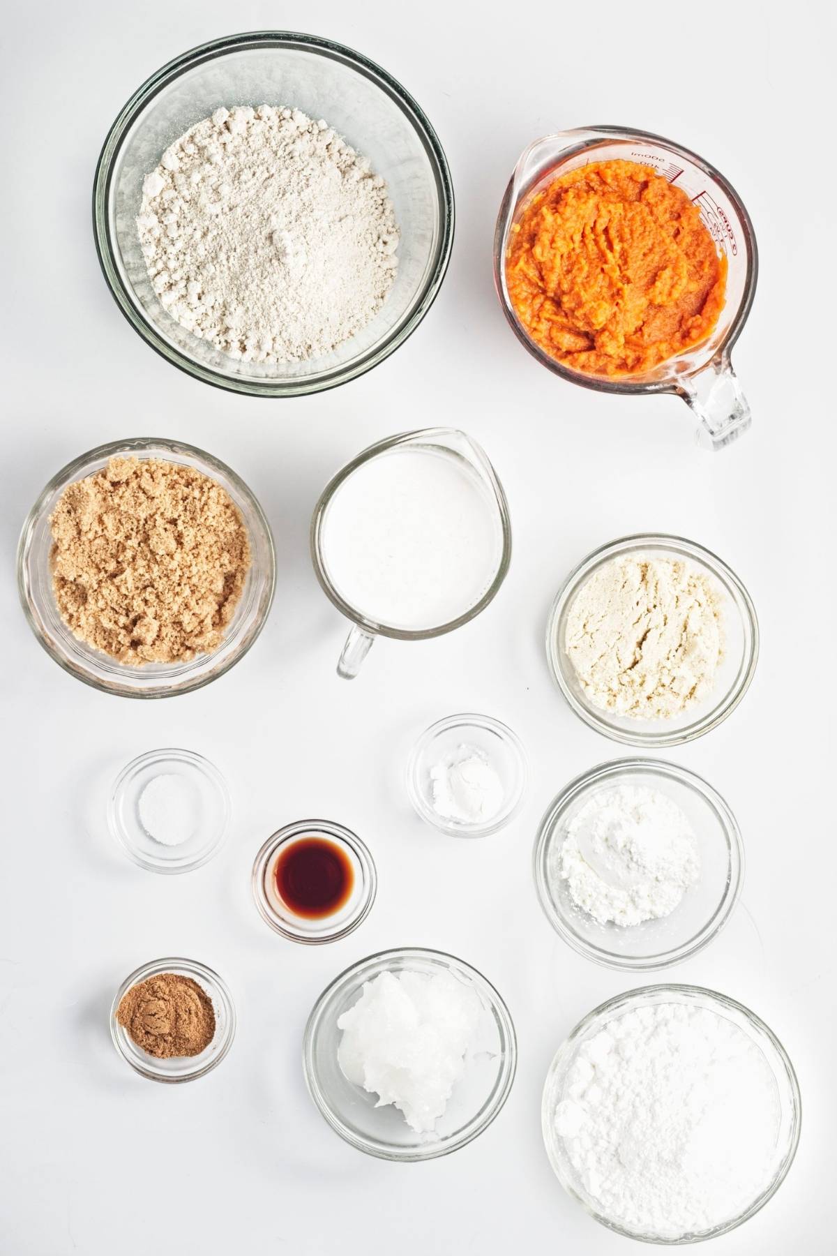 Measured ingredients in bowls and measuring cups on a white surface.