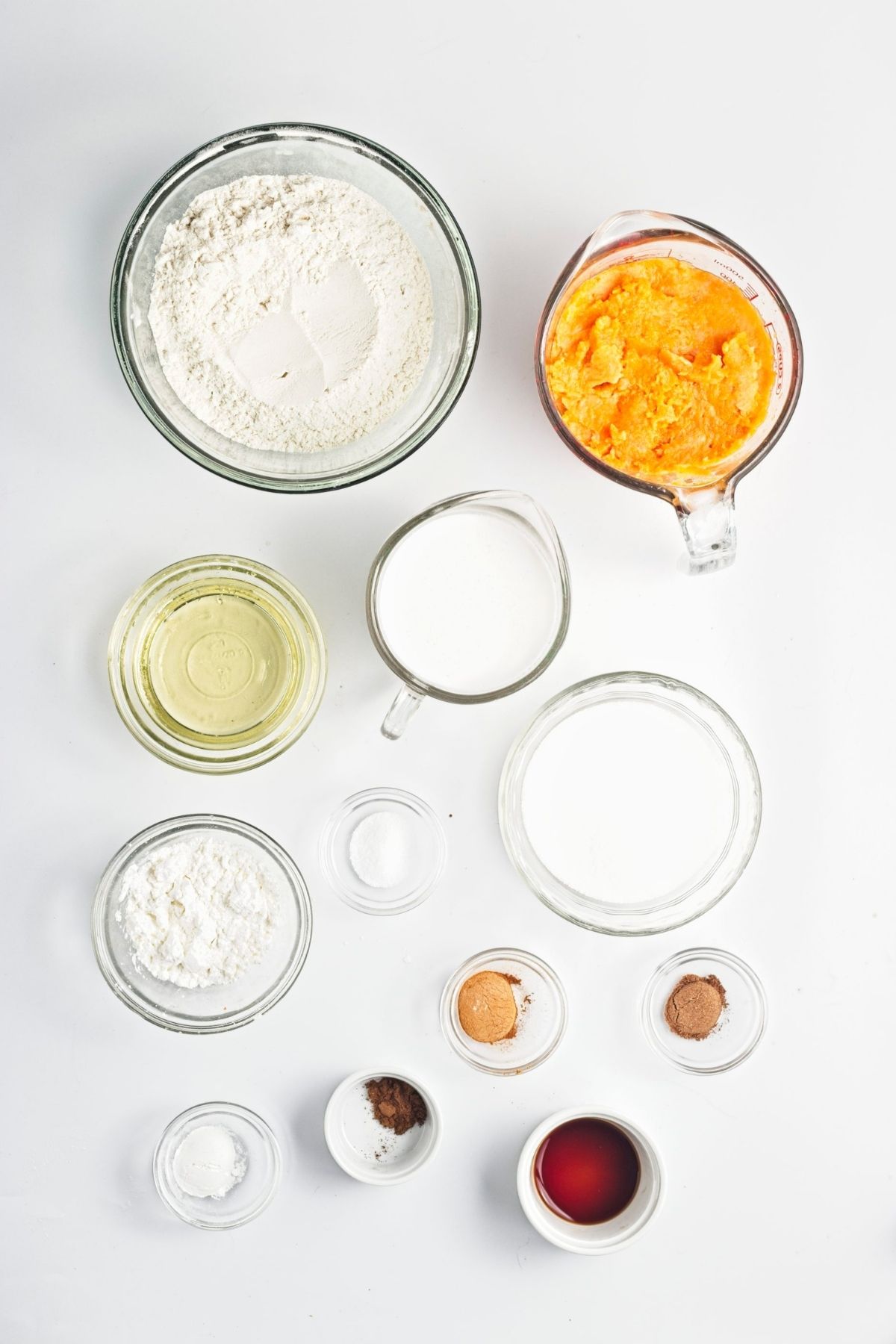 Measured ingredients arranged in bowls and cups on a white surface.