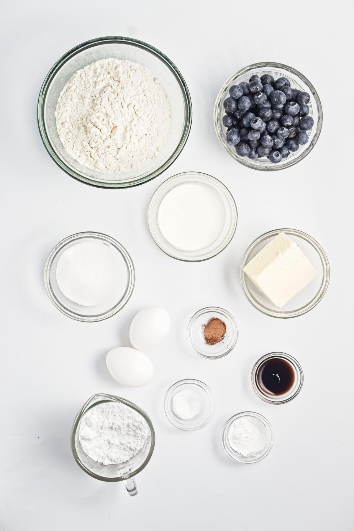 Flour, blueberries, sugar, coconut cream, coconut oil, vanilla, and baking ingredients arranged in bowls.