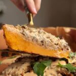 Slice of stuffed butternut squash with rice filling and tahini sauce being lifted with a spatula.