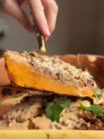 Slice of stuffed butternut squash with rice filling and tahini sauce being lifted with a spatula.