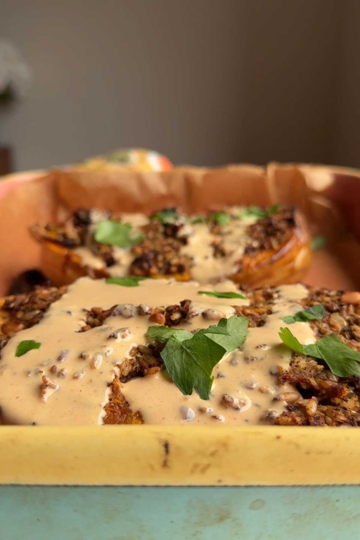 Stuffed butternut squash topped with creamy tahini sauce, parsley, and toasted pine nuts.