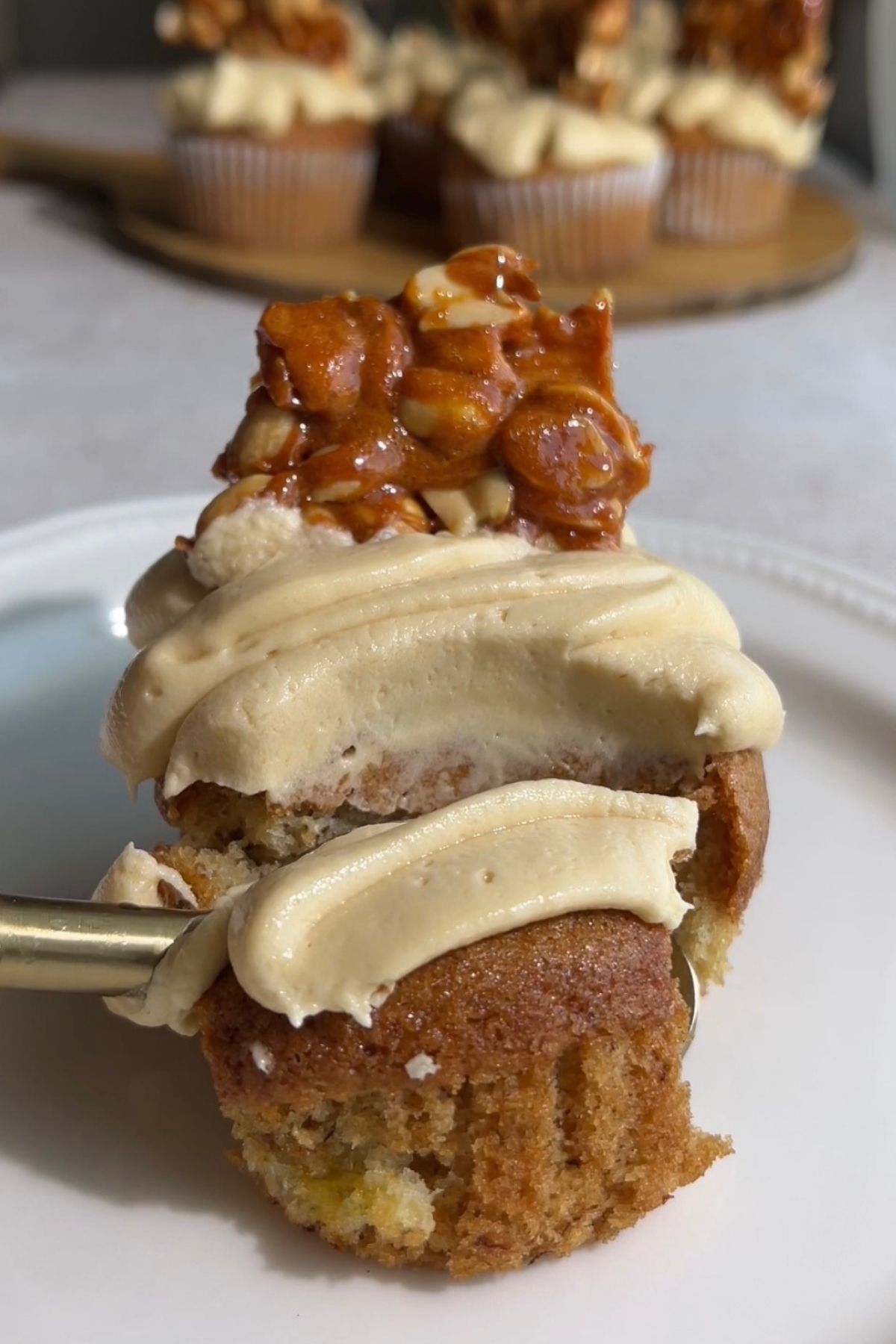 Bitten cupcake showing a soft banana crumb, peanut butter frosting, and peanut brittle.