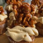 Cupcake with peanut butter frosting topped with peanut brittle.