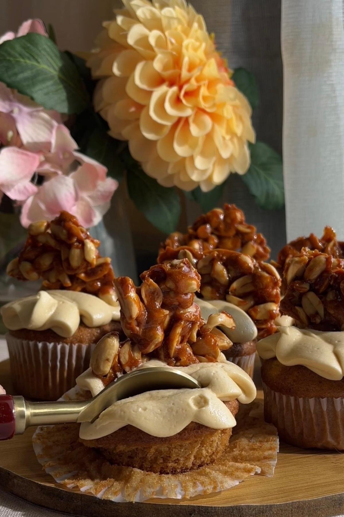 Spoon cutting into a frosted cupcake topped with peanut brittle.