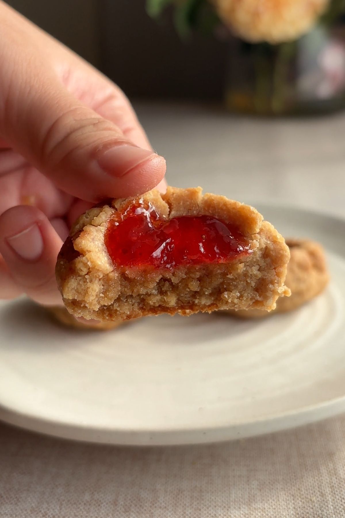 Bitten almond butter thumbprint cookie showing a soft crumb and strawberry jam filling.