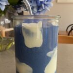 Blue spirulina smoothie with creamy yogurt swirls in a glass jar with a reusable glass straw.