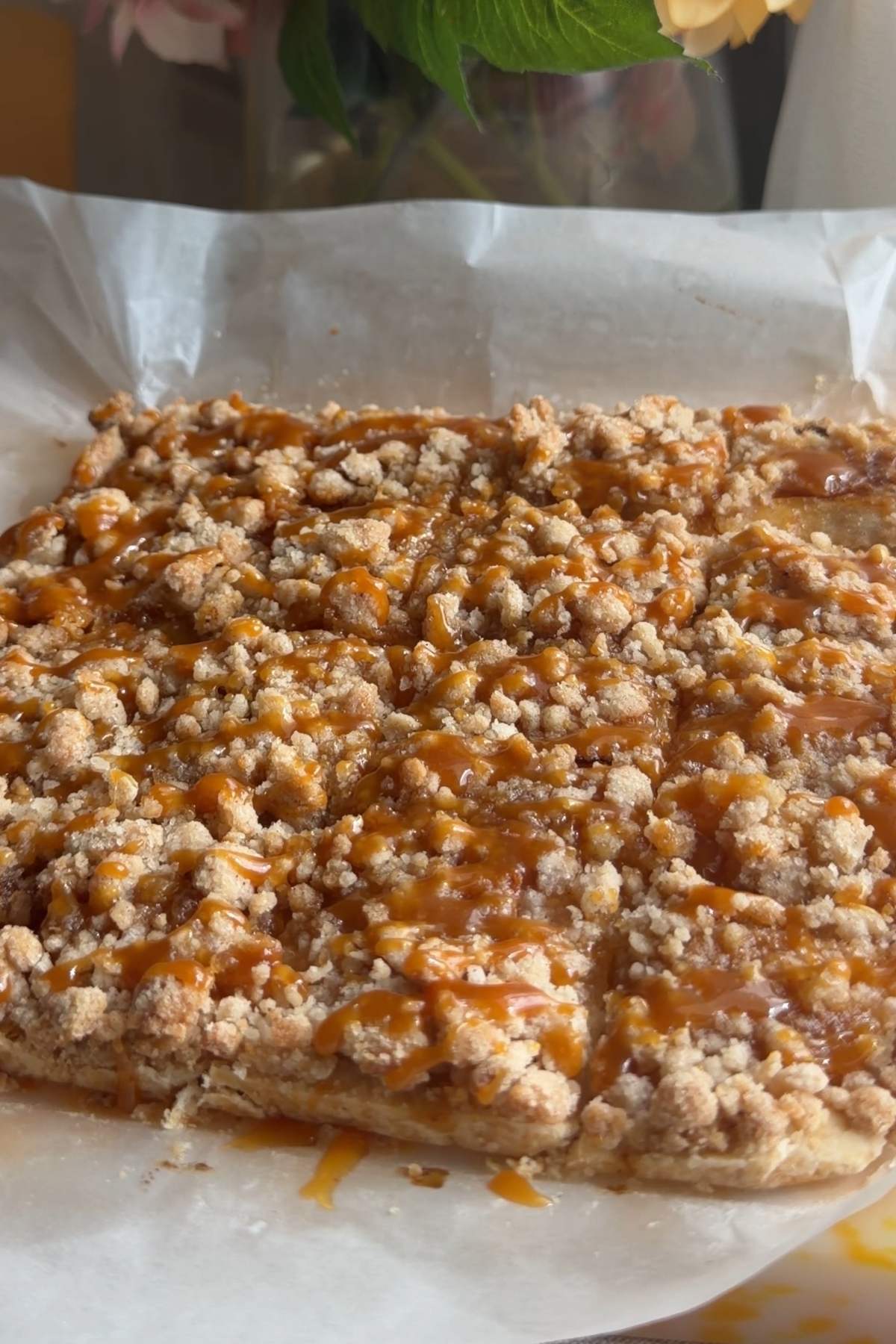 Whole pan of caramel apple crumb bars topped with crumble and caramel drizzle.