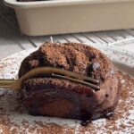 Chocolate cinnamon roll with a fork cutting into the soft, gooey center.
