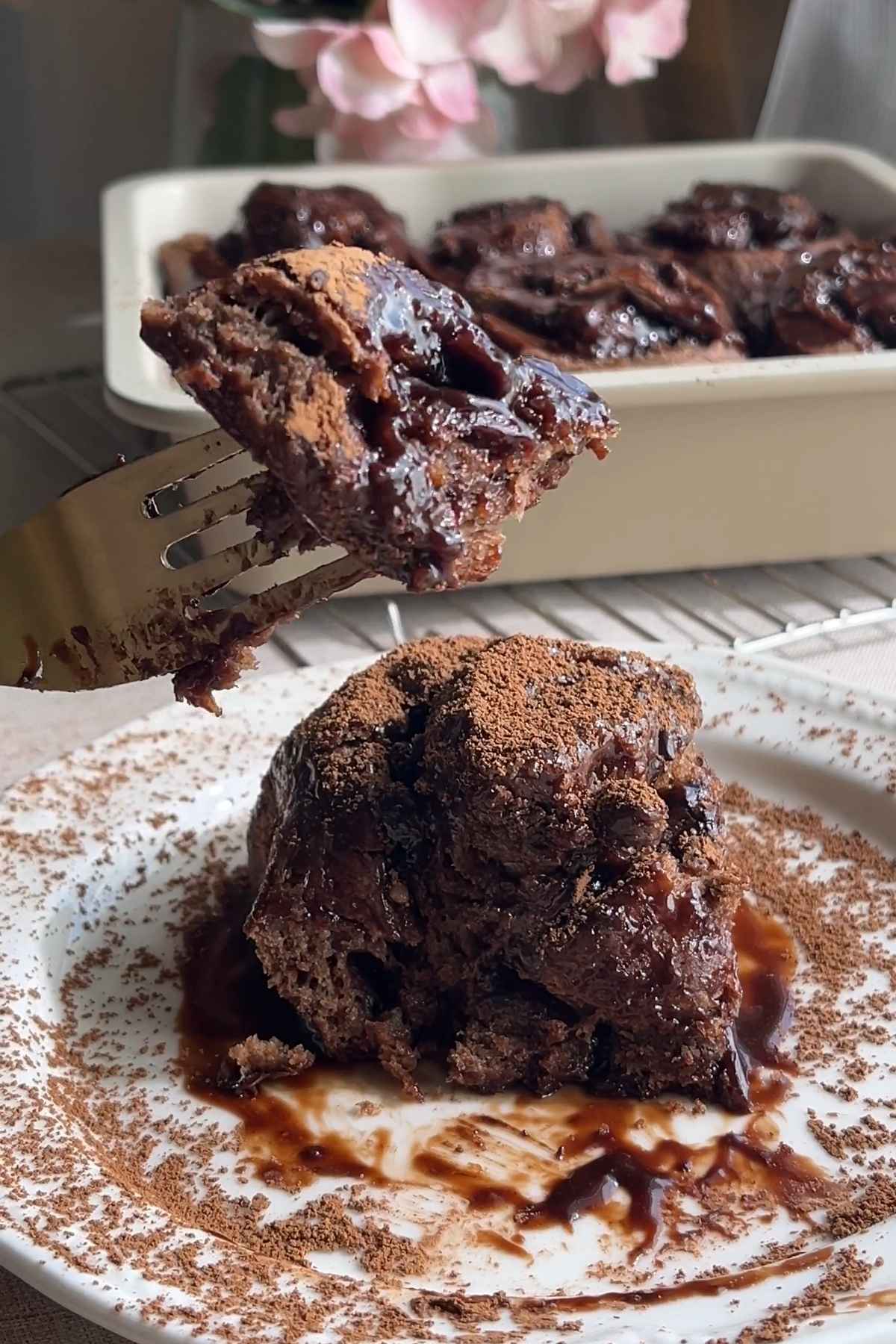 Fork lifting a gooey chocolate cinnamon roll to reveal the soft, chocolatey center.