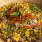 Brown rice bowl topped with avocado, red bell pepper, creamy chipotle dressing, and green onions.