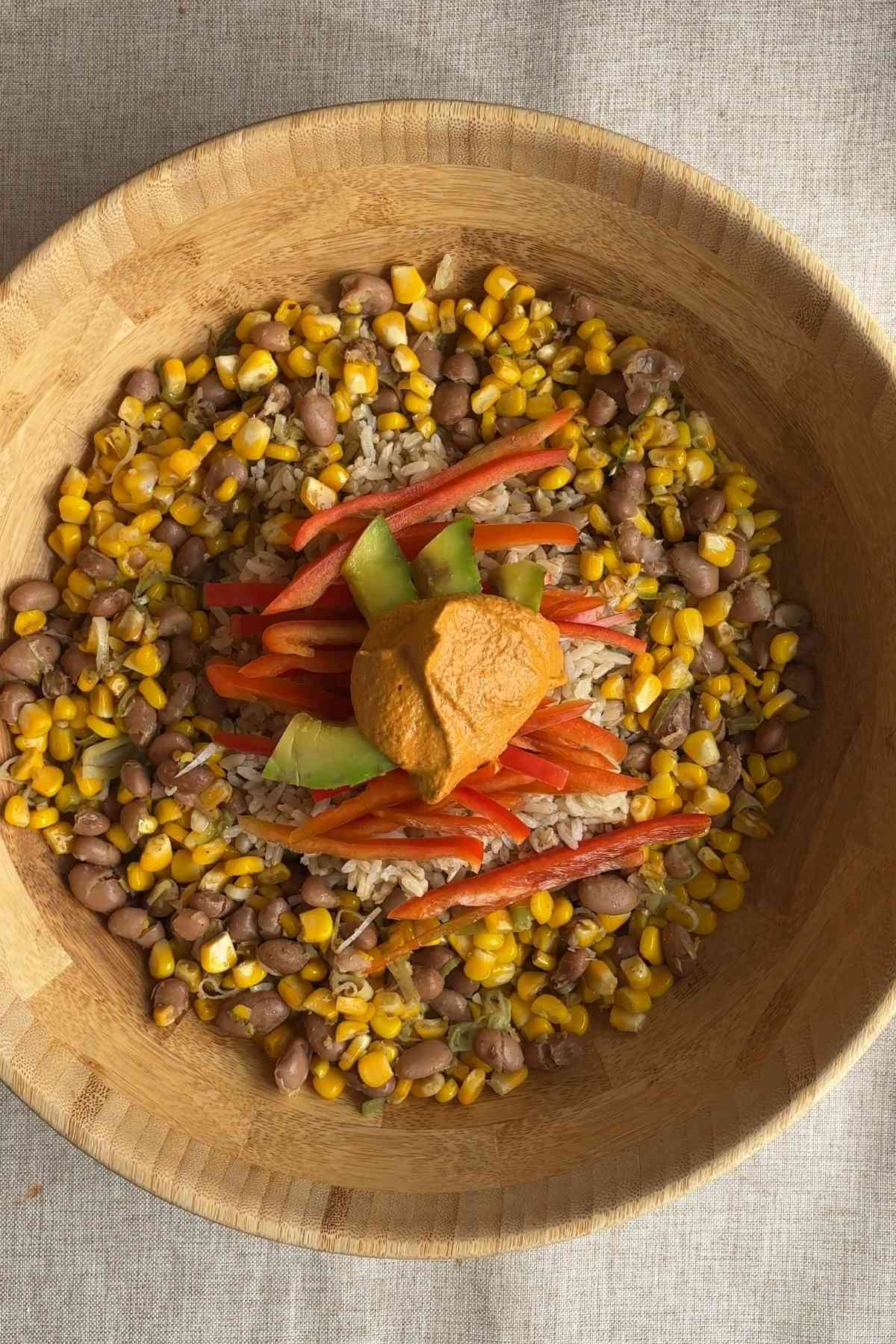 Brown rice bowl with corn, pinto beans, avocado, red bell pepper, and creamy chipotle dressing.
