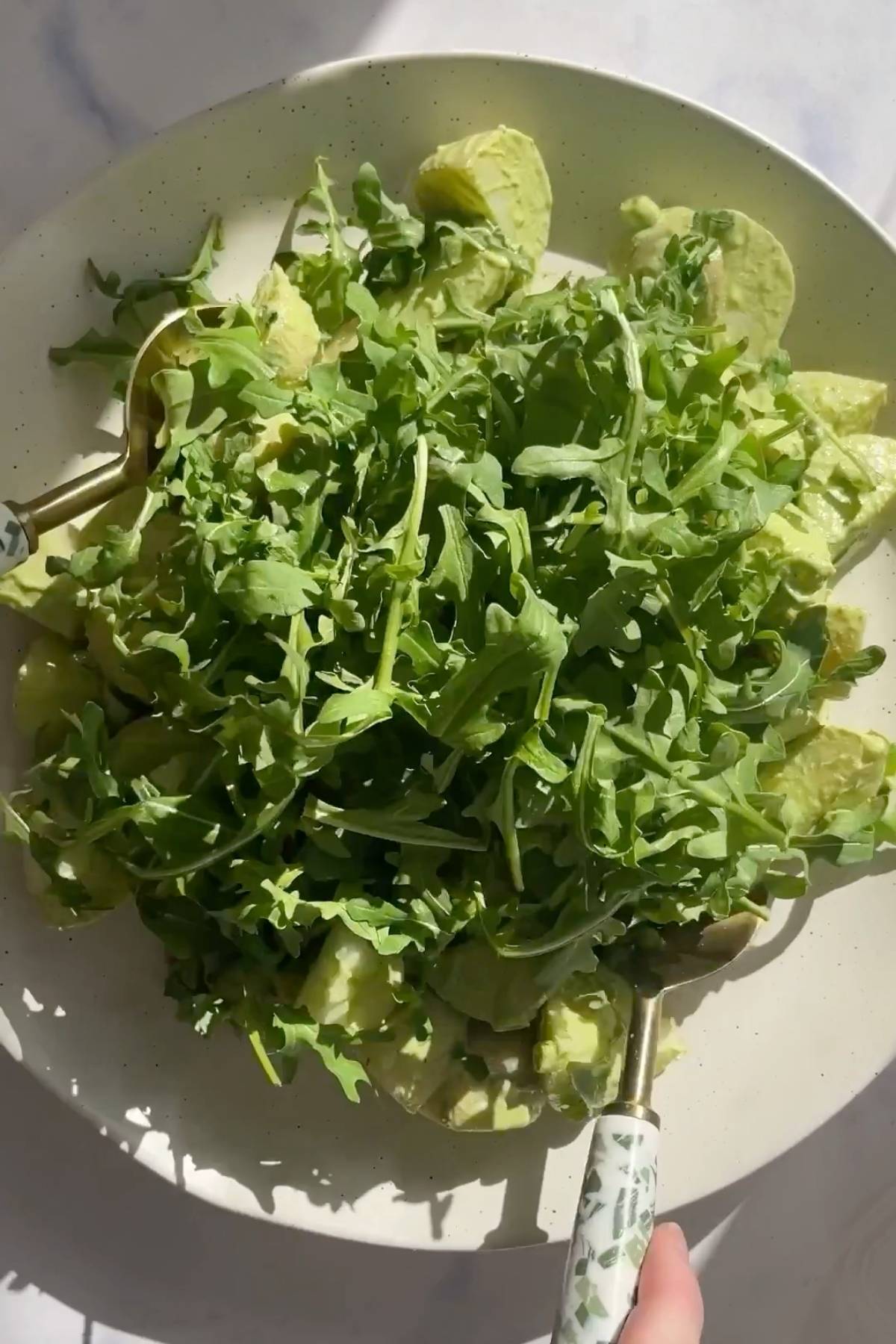 Large bowl of green potato salad with baby potatoes, avocado, and fresh arugula.