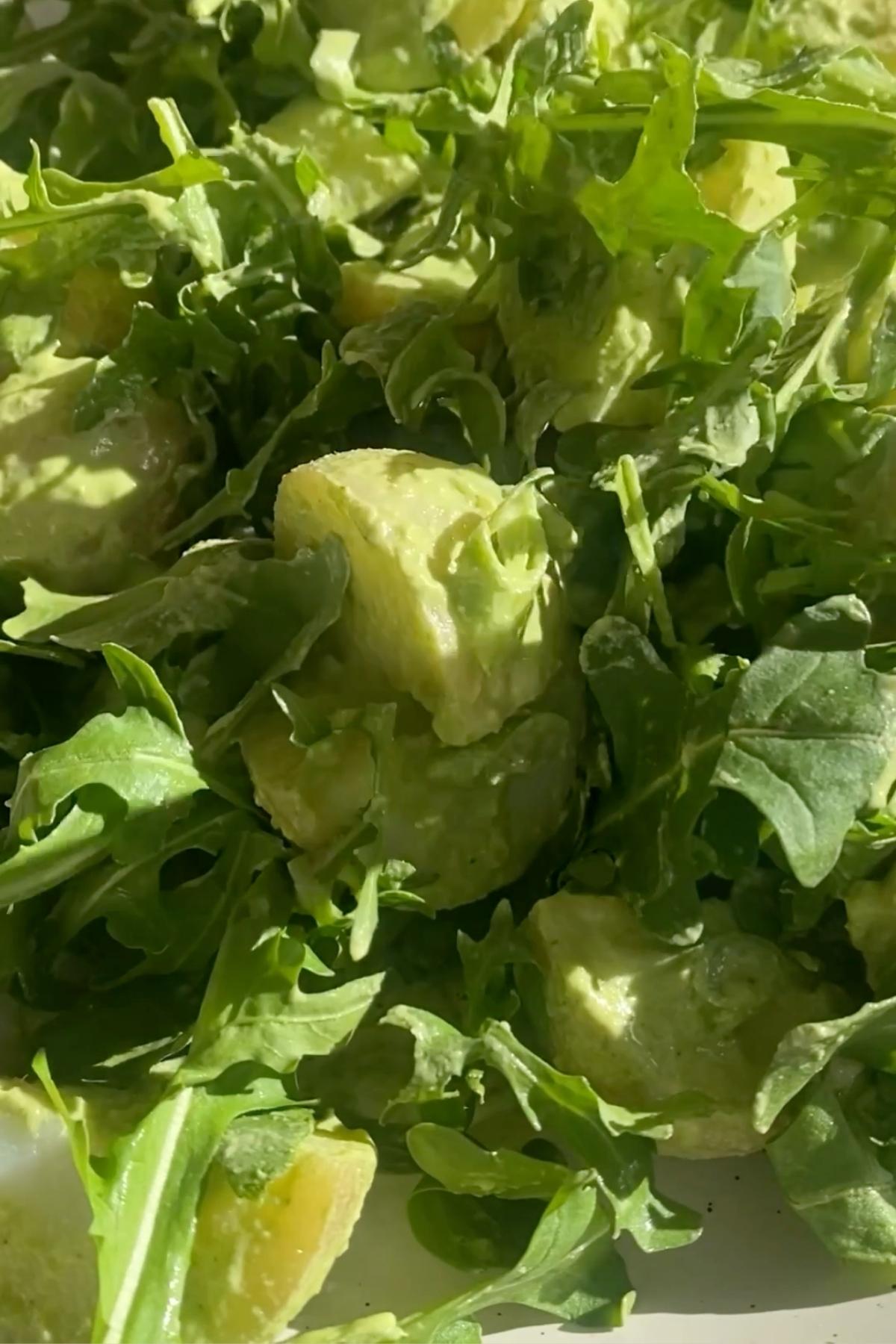 Creamy green potato salad with baby potatoes, avocado, and arugula in a serving bowl.