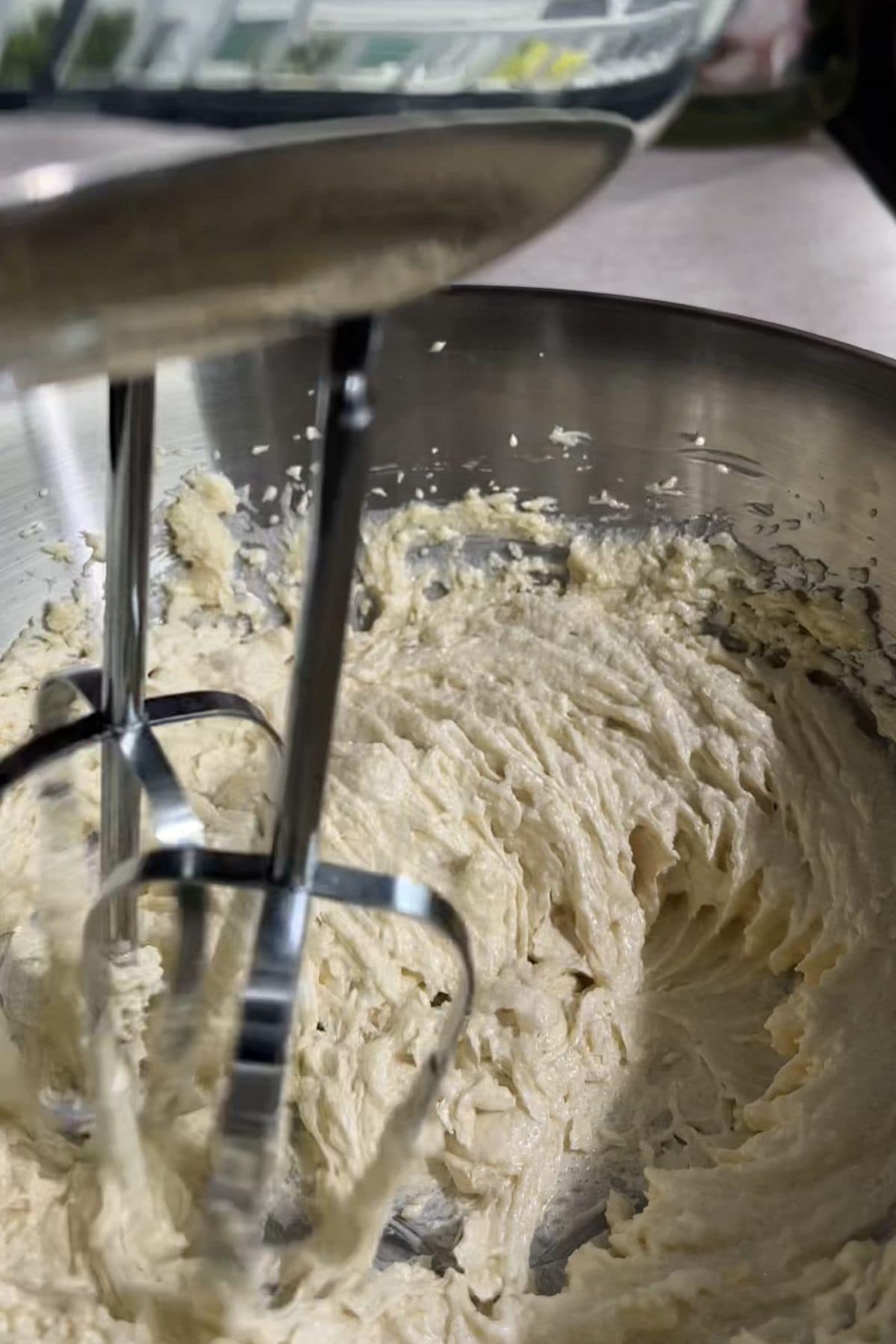 Pale creamed butter and sugar in a metal mixing bowl with electric beaters.