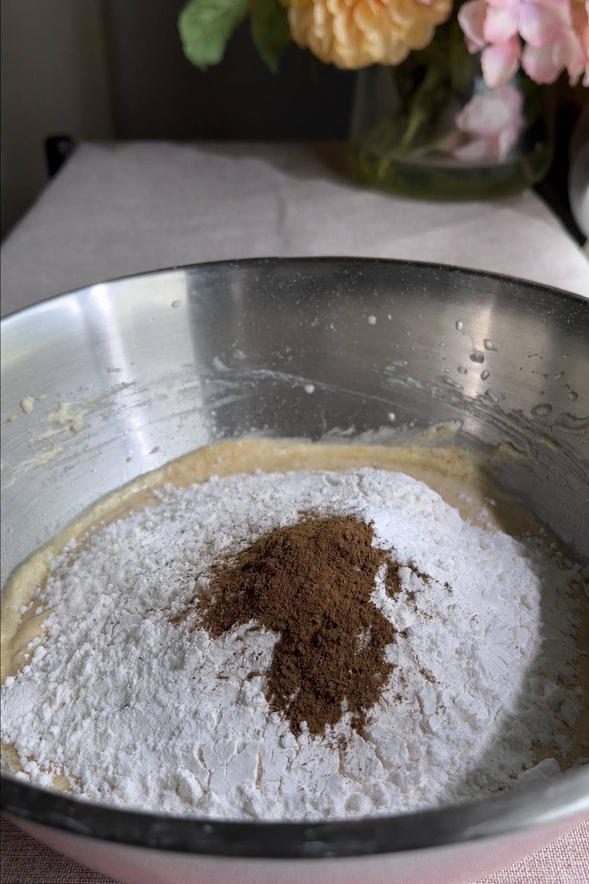 Flour and a mound of cinnamon added on top of the creamed mixture in a bowl.