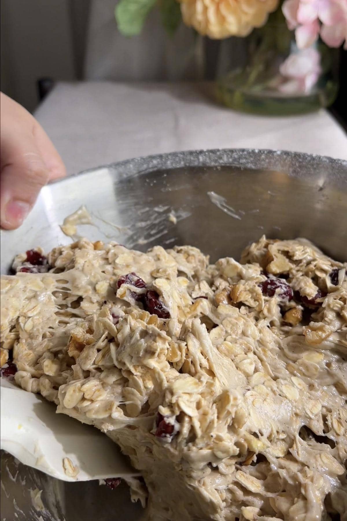 Spatula folding oats, dried cranberries and walnuts through cookie dough.