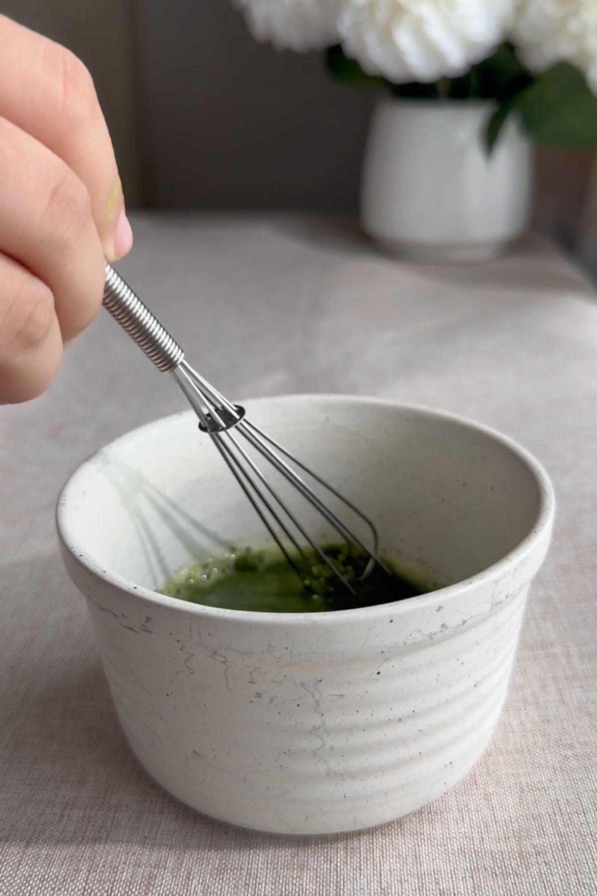Matcha mixture being whisked in a small ceramic bowl.