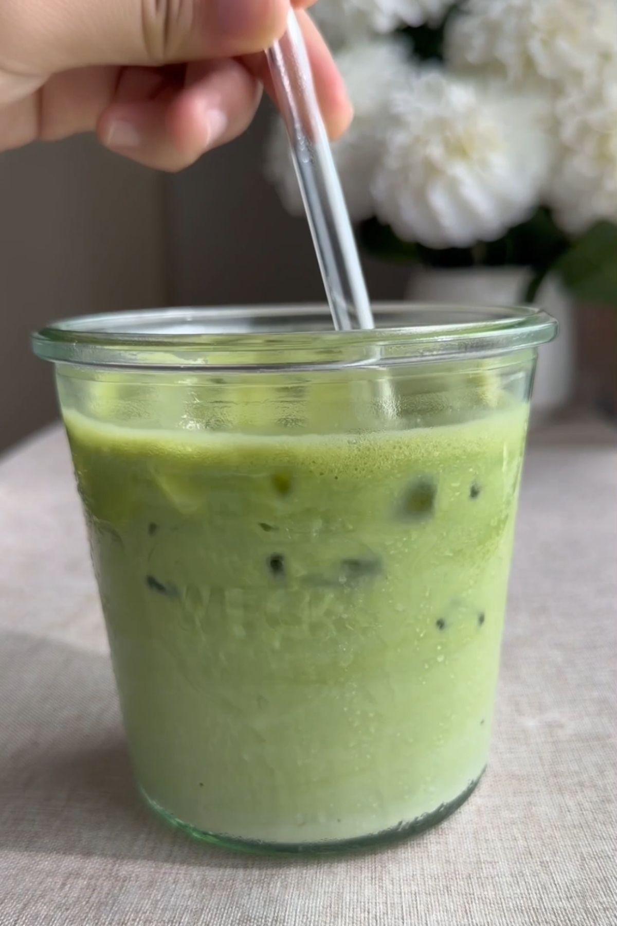 Iced green latte being stirred in a glass.