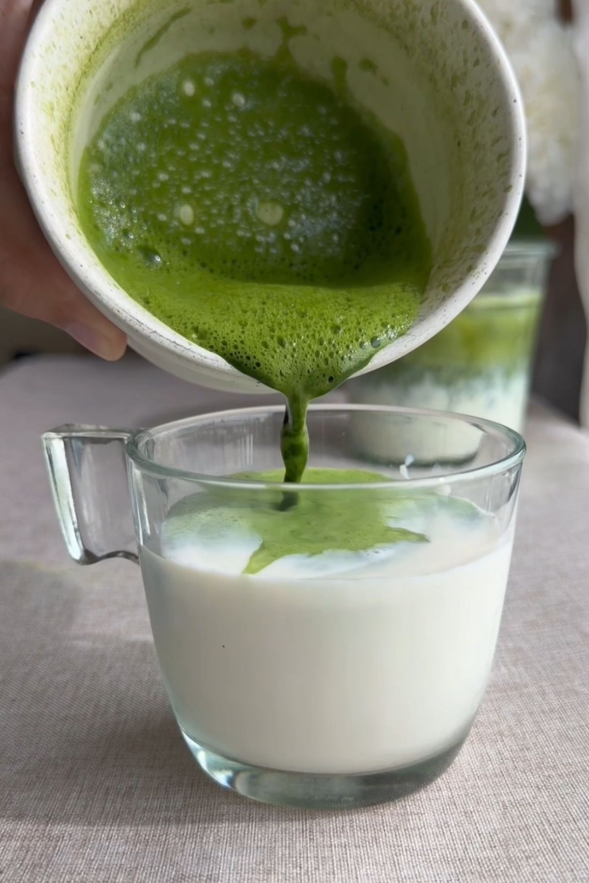 Matcha mixture being poured into milk.