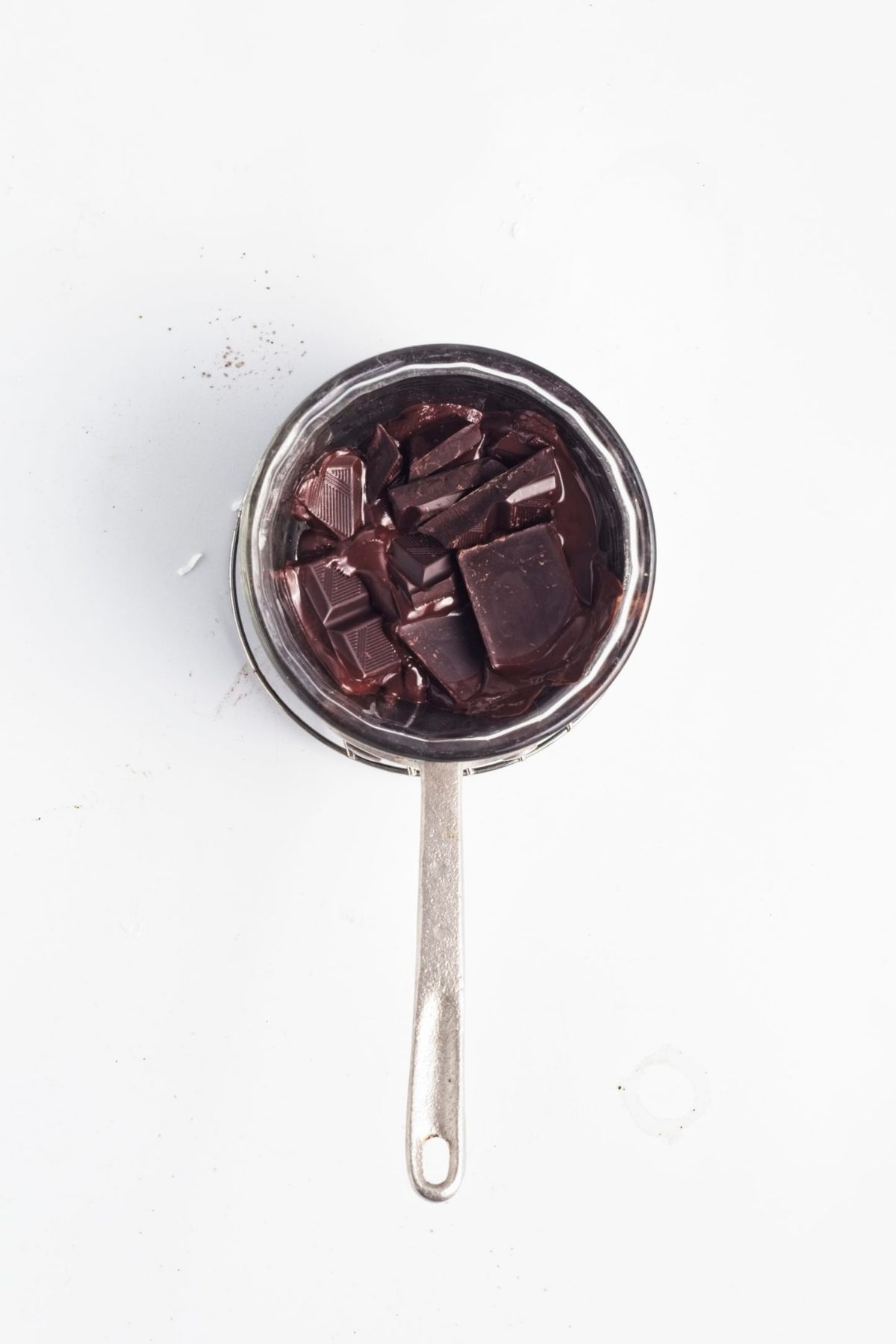 Dark chocolate pieces melting in a small saucepan.