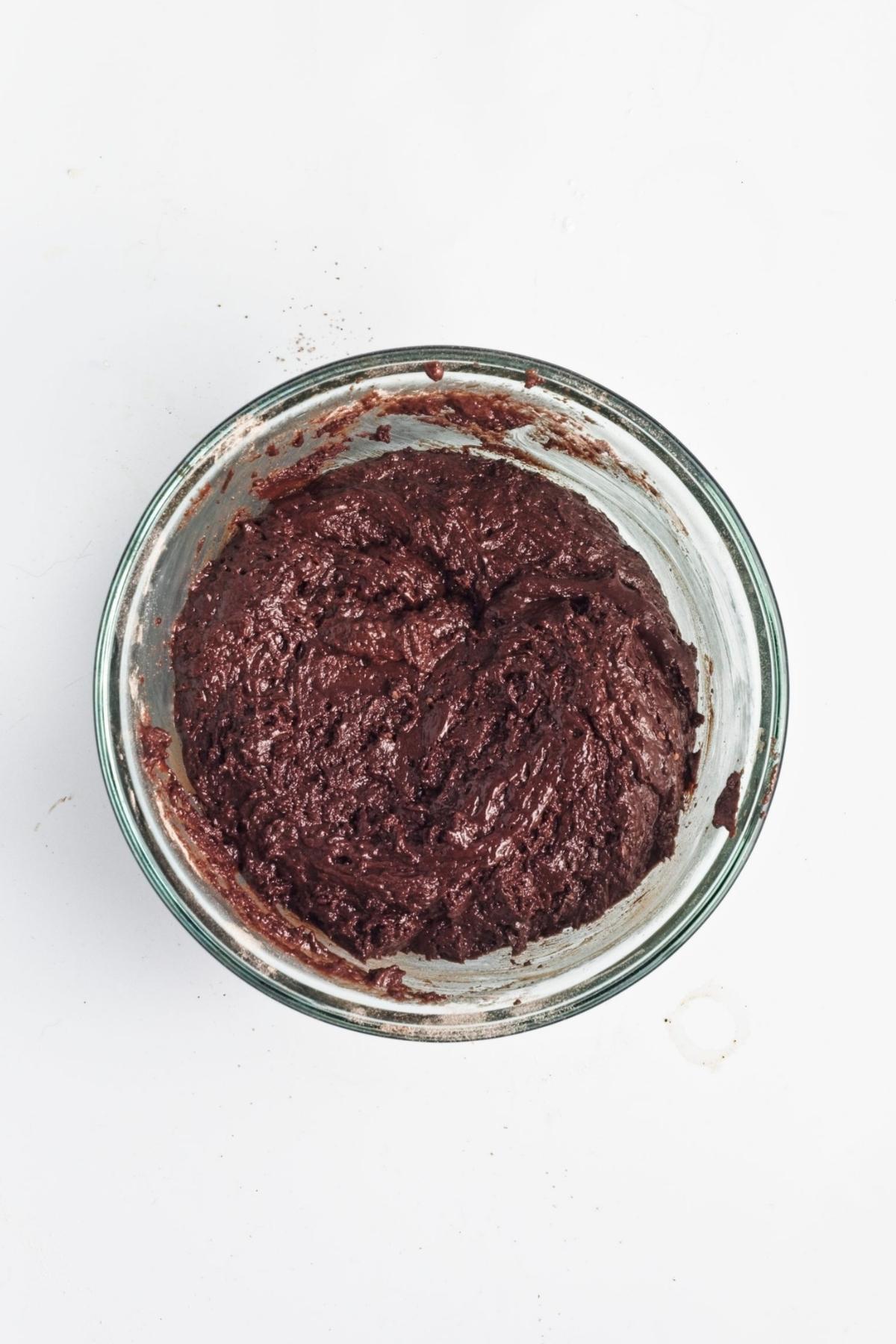 Thick chocolate cake batter mixed in a glass bowl.