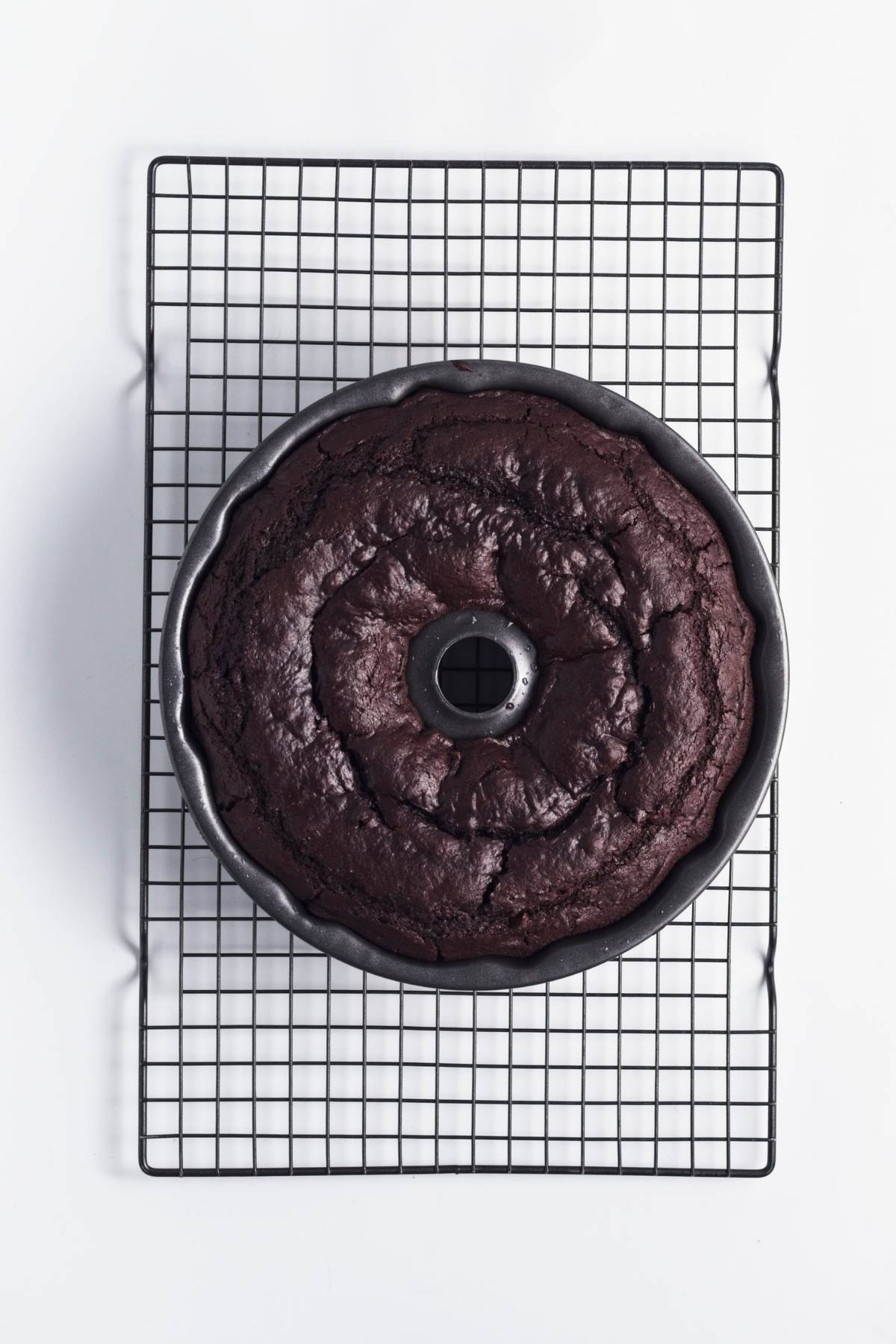 Baked chocolate Bundt cake cooling in the pan on a wire rack.