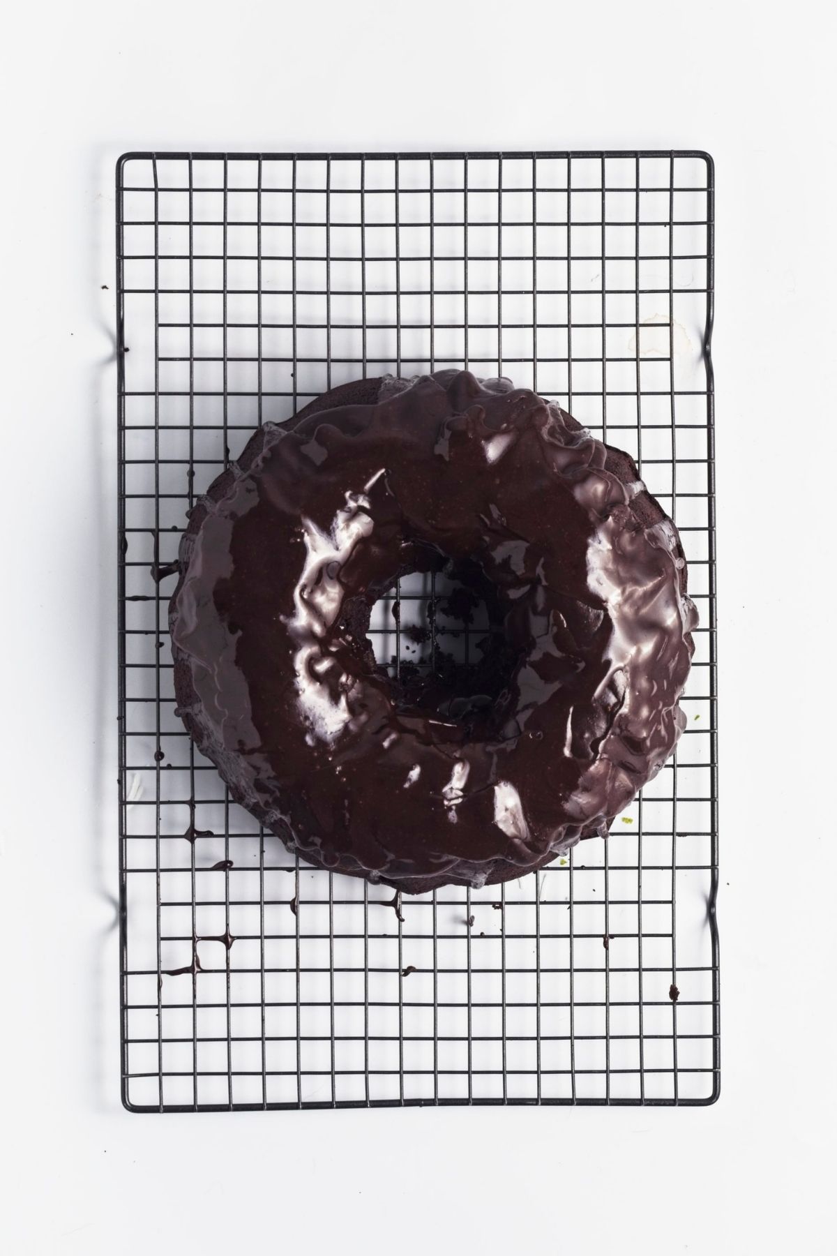 Chocolate Bundt cake covered with glossy icing on a wire rack.