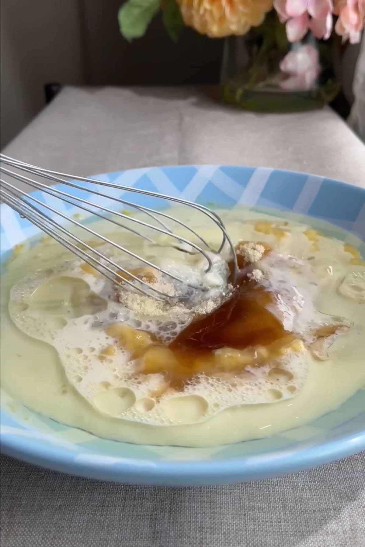 Plant-based milk, vanilla, sugar, oil and mashed banana being whisked in a bowl.