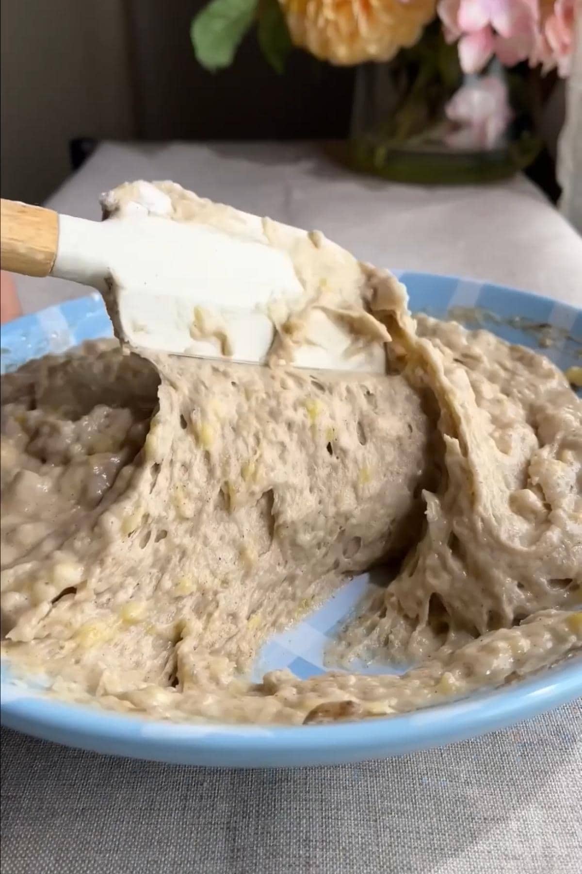 Muffin batter being folded with a spatula in a mixing bowl.