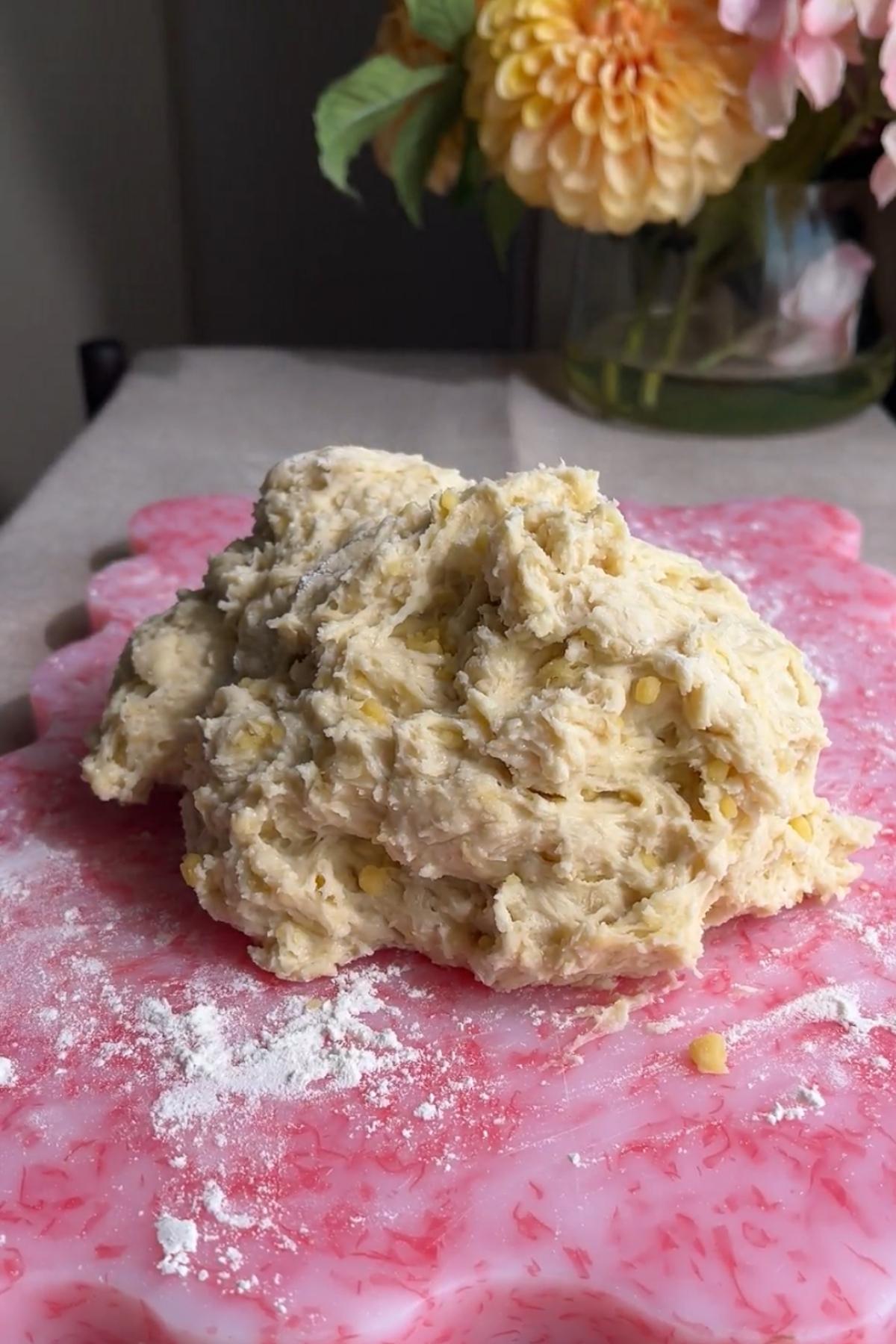 Sticky dough on a floured pink board before kneading.
