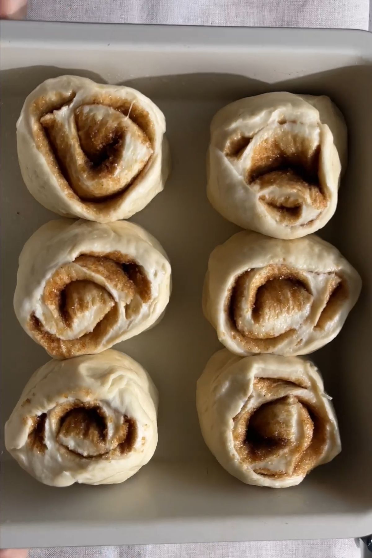 Unbaked cinnamon rolls arranged in a baking dish.