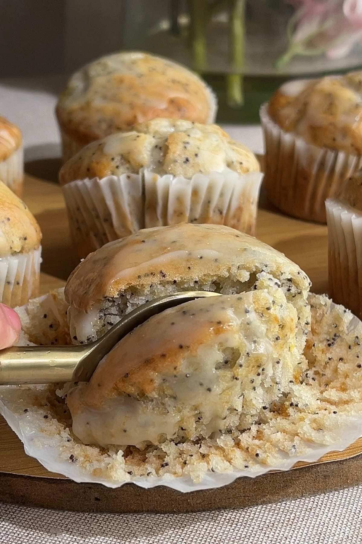 Spoon lifting a glazed piece from a lemon poppy seed muffin.