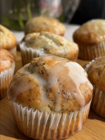 Glazed lemon poppy seed muffin with icing dripping down the sides.