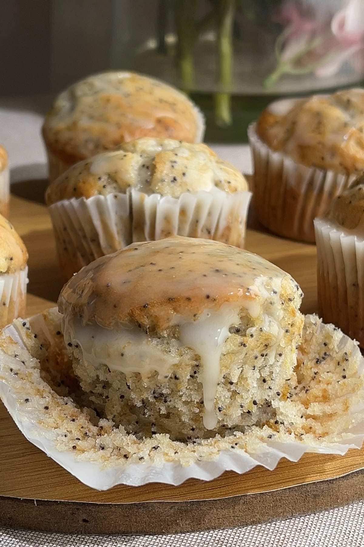 Lemon poppy seed muffin with glaze and paper liner peeled back.