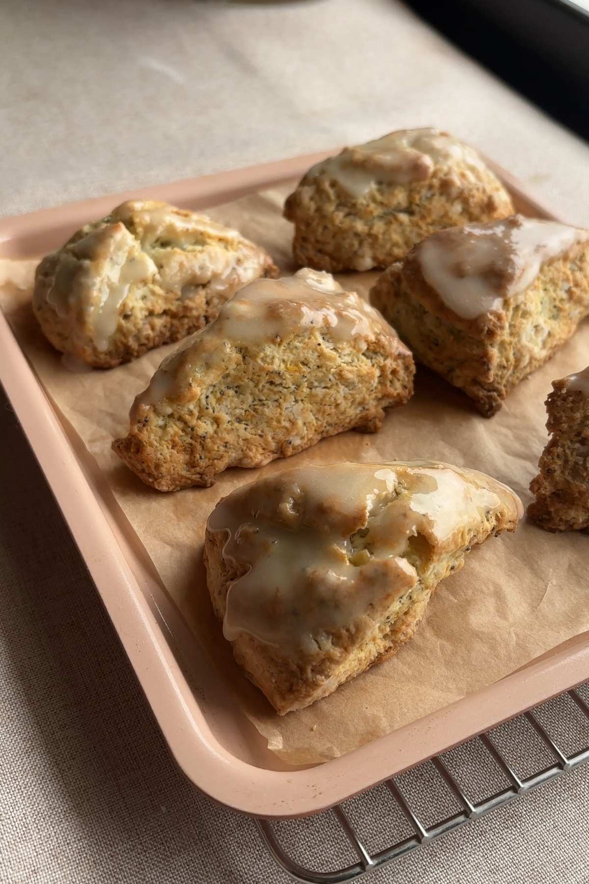 Glazed lemon poppy seed scones arranged on a parchment-lined tray.
