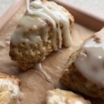 Lemon glaze being poured over freshly baked lemon poppy seed scones.