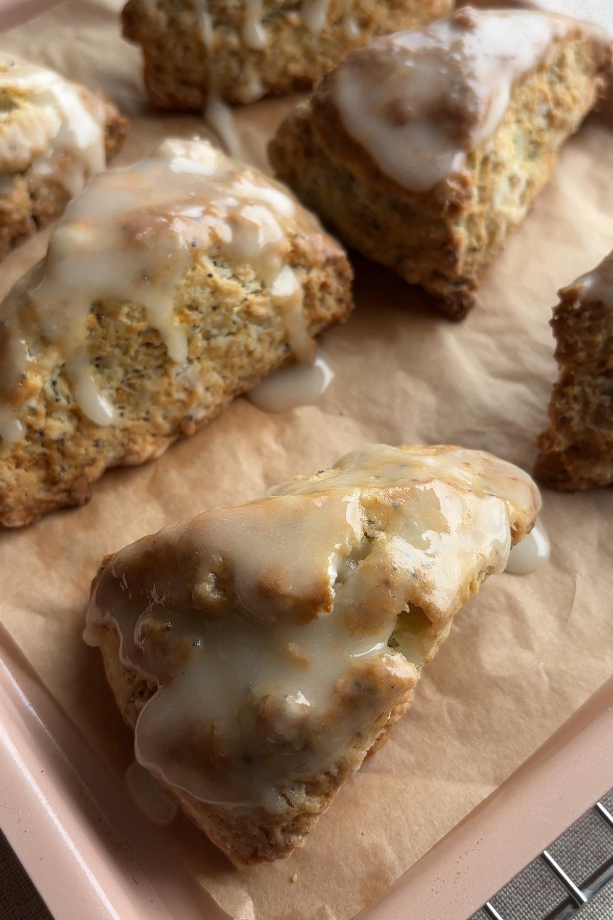 Glazed lemon poppy seed scones on a parchment-lined tray.