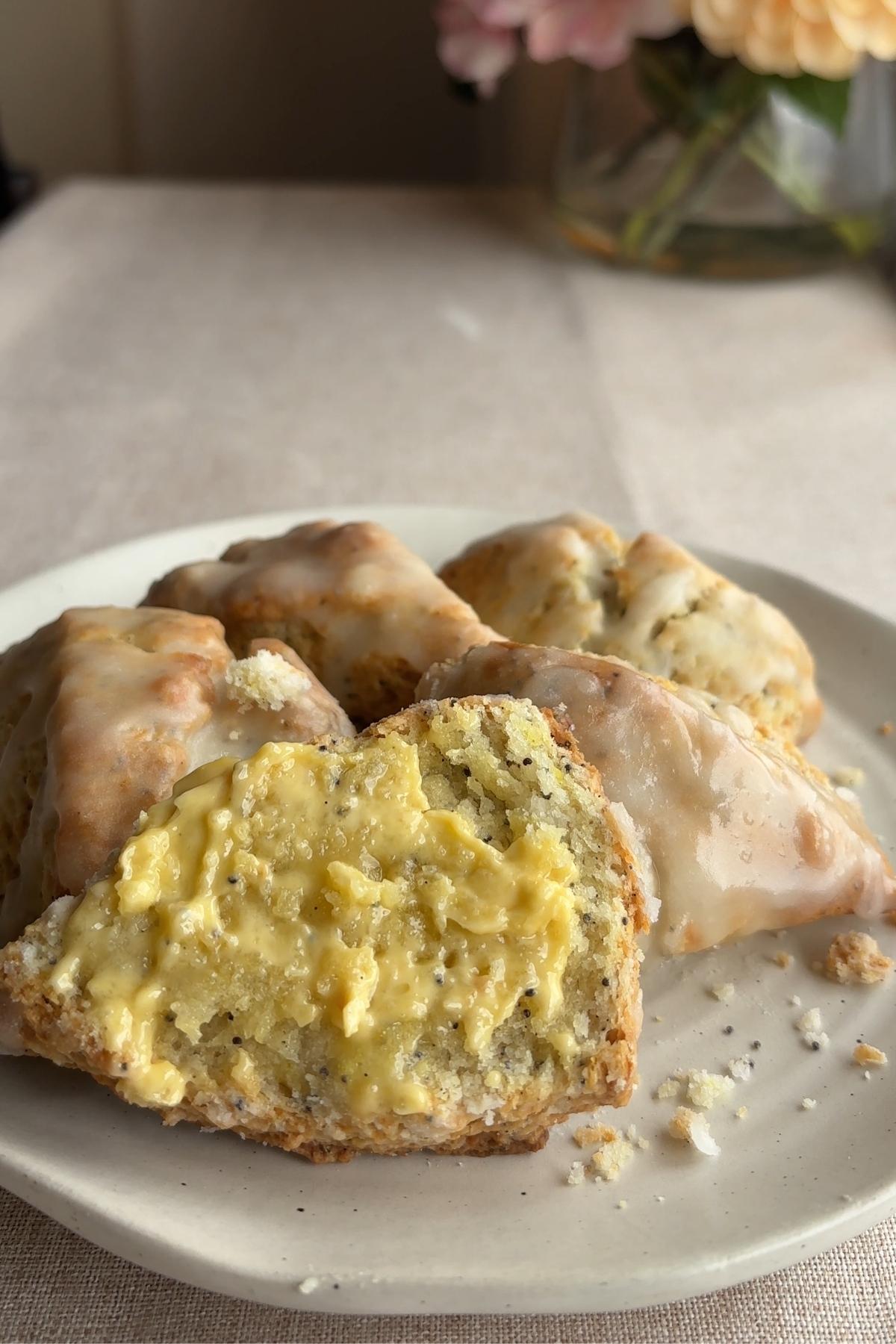 Lemon poppy seed scone split open with lemon curd on a white plate.