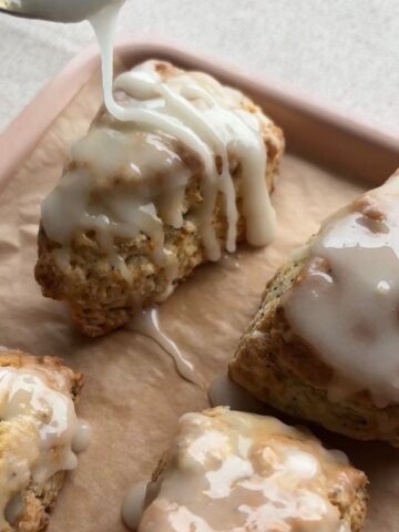 Lemon glaze being poured over freshly baked lemon poppy seed scones.