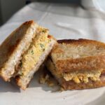 Sliced mashed chickpea sandwich on a white plate.