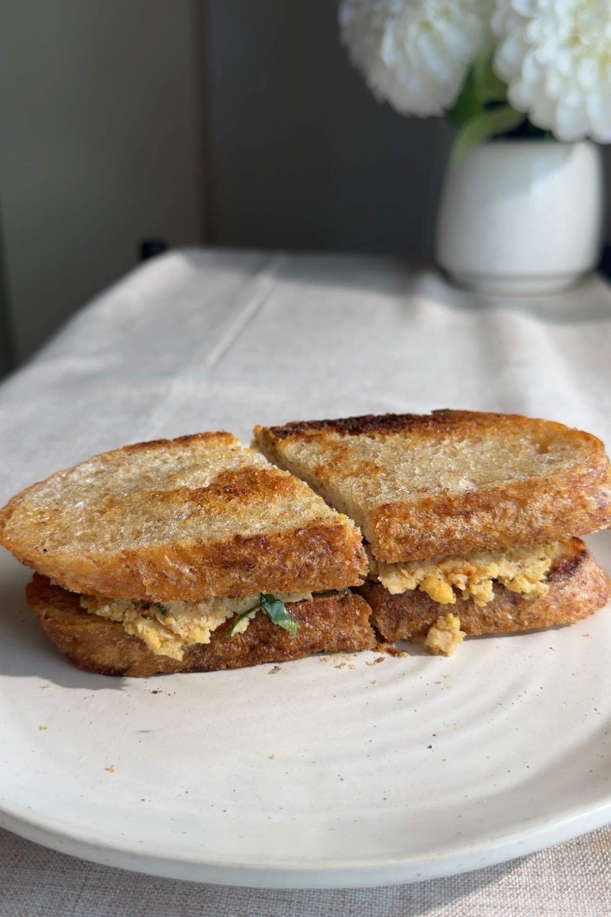 Sliced mashed chickpea sandwich on a white plate.
