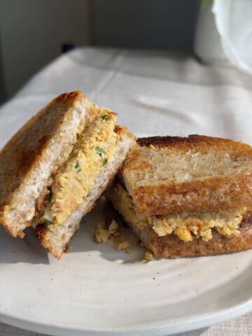 Sliced mashed chickpea sandwich on a white plate.